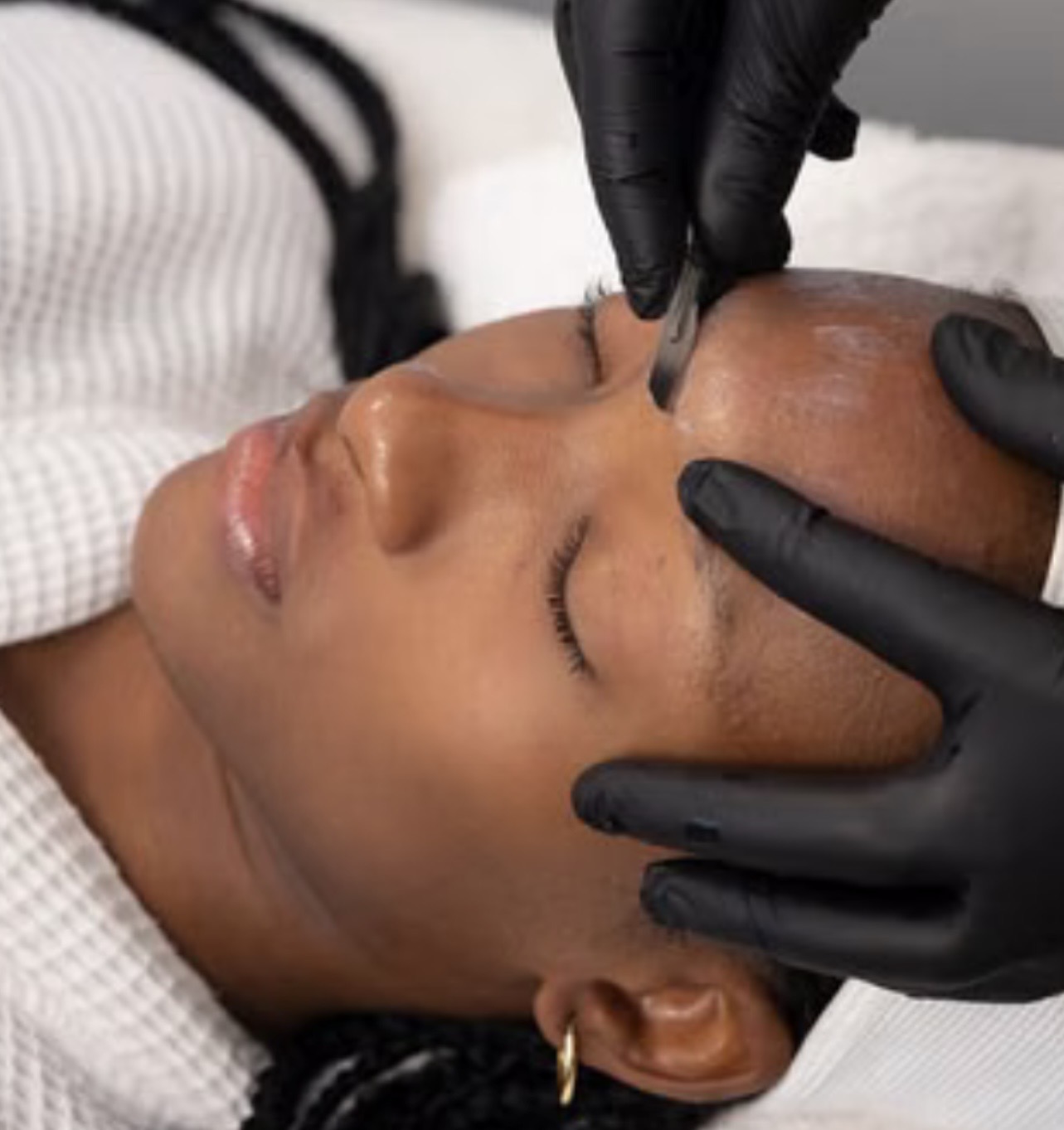 image of Michelle performing a Dermaplaning on a patient with dark skin tone